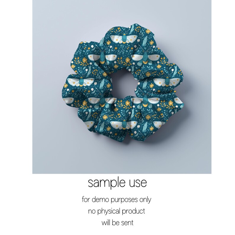 May include: A teal blue scrunchie with a white and gold floral pattern featuring moths. The pattern is repeated throughout the scrunchie.