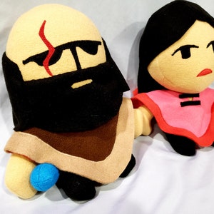 May include: Two plush toys, one with a brown beard and a red scar on its forehead, the other with black hair and a pink shirt.