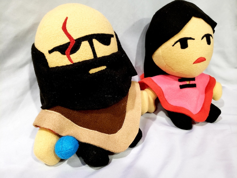 May include: Two plush toys, one with a brown beard and a red scar on its forehead, the other with black hair and a pink shirt.