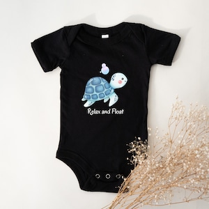 Op de afbeelding: Zwarte baby romper met een illustratie van een blauwe en groene schildpad en de tekst "Relax and Float".