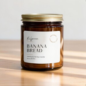 May include: A brown glass jar candle with a gold metal lid and a white label. The label features the text Belgreen, BANANA BREAD, Hand-poured Soy Candle, 8 oz | 65 hrs, and a circular stamp reading NATURAL ECO-FRIENDLY.