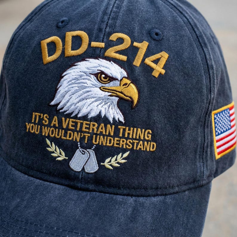 May include: Navy blue baseball cap with embroidered text and graphics. The cap features the text "DD-214", an eagle, the phrase "IT'S A VETERAN THING YOU WOULDN'T UNDERSTAND", dog tags, and an American flag patch.