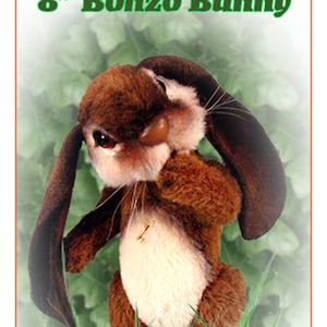 Puede incluir: Un conejo de peluche marrón y blanco de 20 cm con orejas largas y caídas. El conejo está de pie en un parche de hierba verde. El texto "8" Bonzo Bunny" está en la parte superior de la imagen. El texto "My Secret Garden" está en la parte inferior de la imagen.