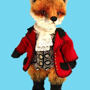 May include: A plush fox wearing a red jacket with black trim, a white lace collar, and a black and gold patterned vest. The fox has black eyes and a black nose.