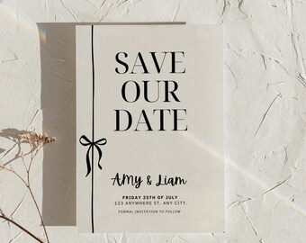 May include: Save the date card with a black ribbon and the text "SAVE OUR DATE" in large, bold letters. The card also includes the names "Amy & Liam", the date "FRIDAY 25TH OF JULY", the address "123 ANYWHERE ST. ANY CITY.", and the text "FORMAL INVITATION TO FOLLOW".