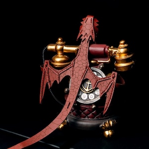 May include: A red dragon-shaped phone with a gold rotary dial and a black cord. The phone is on a black background.
