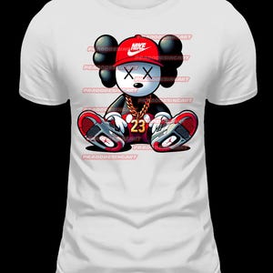 K&ouml;nnte beinhalten: Wei&szlig;es T-Shirt mit einer Cartoon-Illustration eines schwarz-wei&szlig;en Charakters, der einen roten Nike-Hut, eine goldene Kette und rote und schwarze Turnschuhe tr&auml;gt. Der Charakter hat ein 'X' f&uuml;r Augen und die Nummer '23' auf seiner Brust.