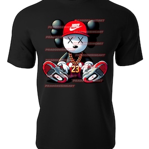 K&ouml;nnte beinhalten: Schwarzes T-Shirt mit einer Cartoon-Illustration eines Mickey-Mouse-Charakters, der einen roten Nike-Hut, eine goldene Kette und rote und wei&szlig;e Turnschuhe tr&auml;gt. Der Charakter hat ein X f&uuml;r Augen und die Nummer 23 auf seiner Brust.