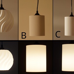 Pu&ograve; includere: Un set di tre lampade a sospensione con diversi paralumi. La prima ha un design bianco a spirale, la seconda ha delle scanalature verticali e la terza &egrave; un cilindro liscio. Tutte hanno cavi e raccordi neri.