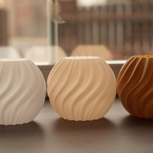 Pu&ograve; includere: Tre vasi decorativi sferici con un design a spirale e strutturato. I vasi sono nei toni del bianco, beige e marrone. I vasi sono probabilmente realizzati in ceramica o materiale simile.