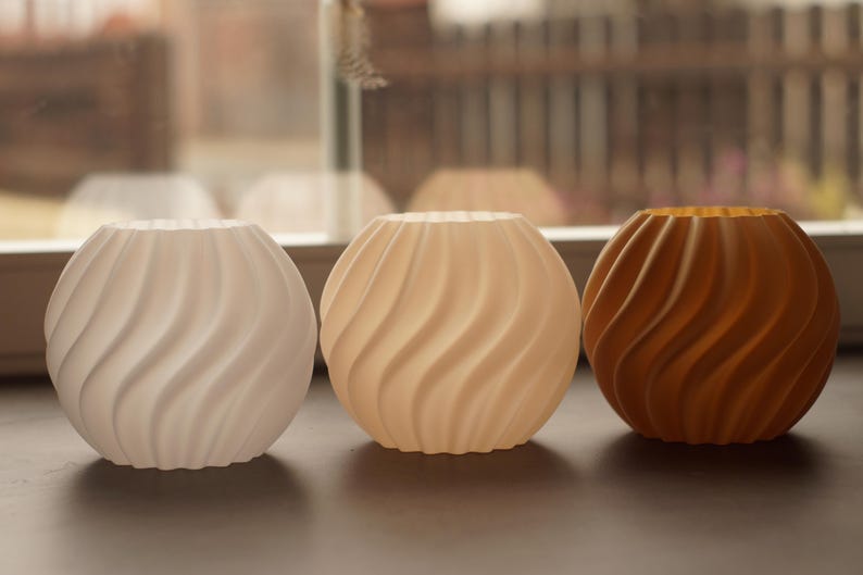 Pu&ograve; includere: Tre vasi decorativi sferici con un design a spirale e strutturato. I vasi sono nei toni del bianco, beige e marrone. I vasi sono probabilmente realizzati in ceramica o materiale simile.