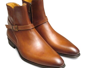 May include: A pair of brown leather ankle boots with a buckle strap and zipper closure.
