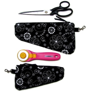 Peut inclure: Un ensemble de deux pochettes en tissu noir avec un motif floral blanc, chacune dotée d'une fermeture éclair et d'un fermoir pivotant en métal. L'ensemble comprend des ciseaux en métal argenté à poignées noires et un cutter rotatif rose et jaune.