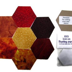 May include: Hexagon-shaped fabric pieces in shades of red, brown, and gold. A template for cutting fabric and a packet of 100 iron-on basting papers are also shown. The papers are 3.18 cm sides when finished.
