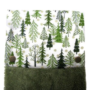 Peut inclure: Une serviette de cuisine verte et blanche avec un motif de forêt. La serviette a un dos en tissu éponge vert et deux boutons en laiton.