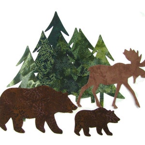 Peut inclure: Un ours brun, un ourson brun plus petit et un élan brun se tiennent devant une forêt d'arbres verts. Les animaux sont découpés dans un tissu à motifs bruns et verts.