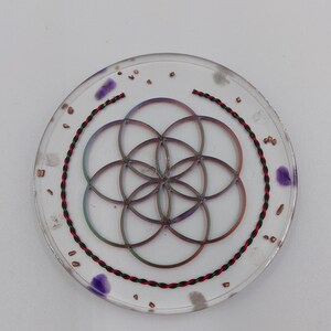 Energy disc cast from epoxy resin, with energized semi-precious stones, rock crystals, rose quartz, amethyst. Borderless flower of life