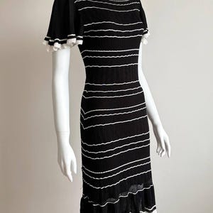 May include: Black and white striped dress with short sleeves and a ruffled hem. The dress is displayed on a mannequin. The dress has a round neckline and a fitted silhouette. The white stripes are horizontal.