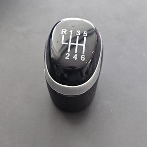 May include: Black leather gear shift knob with a silver ring around the base. The knob has a black plastic top with white numbers and letters indicating the gear positions: R, 1, 3, 5, H, 2, 4, 6.