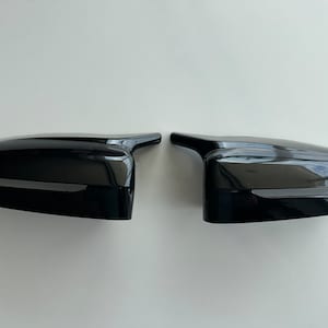 Może przedstawiać: Para czarnych lusterek bocznych do samochodu. Lusterka wykonane są z błyszczącego tworzywa sztucznego.