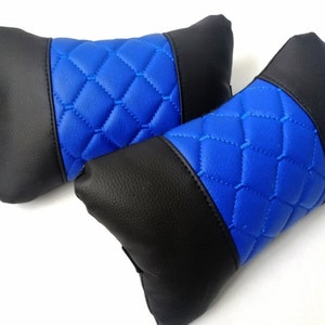 Könnte beinhalten: Zwei Kopfstützenkissen für Autositze. Die Kissen sind schwarz und blau. Der Mittelteil der Kissen ist leuchtend blau mit einem Rautenmuster. Die Enden der Kissen sind schwarz. Die Kissen bestehen aus einem glatten Material.