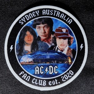 Puede incluir: Un parche circular blanco y negro con un borde blanco. El parche presenta una foto de tres hombres frente a una imagen azul y blanca de la Ópera de Sydney. El texto "Sydney Australia" está en la parte superior del parche, "AC/DC" está en el centro y "Fan Club est. 2020" está en la parte inferior.