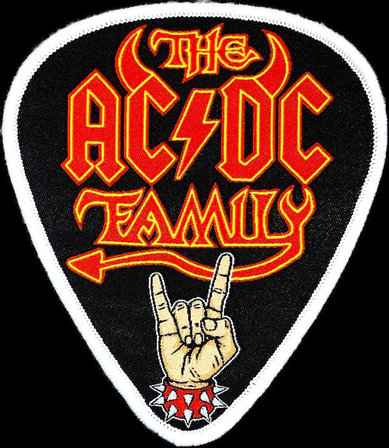 Peut inclure: Un patch noir en forme de m&eacute;diator de guitare avec une bordure blanche. Le patch pr&eacute;sente le texte "The AC/DC Family" en lettres rouges et jaunes avec une queue de diable rouge et une corne de diable jaune. Une main de dessin anim&eacute; avec un bracelet &agrave; pointes fait le geste rock and roll.