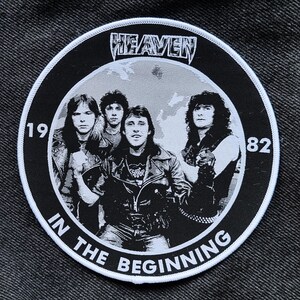 Puede incluir: Un parche circular blanco y negro con el texto "HEAVEN" en una fuente estilizada. El parche también presenta una banda de cuatro personas, el texto "1982" y el texto "IN THE BEGINNING".