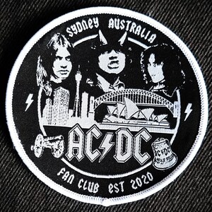 May include: A black and white embroidered patch with the band AC/DC's logo, the Sydney Opera House, and the text "Sydney Australia Fan Club Est 2020".