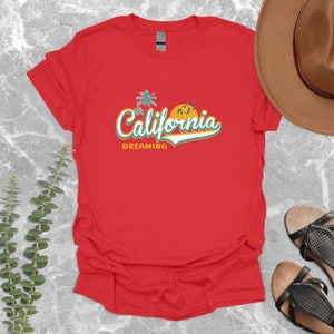 May include: Red t-shirt with a retro-style graphic that says "California Dreaming" with palm trees and a sunset.