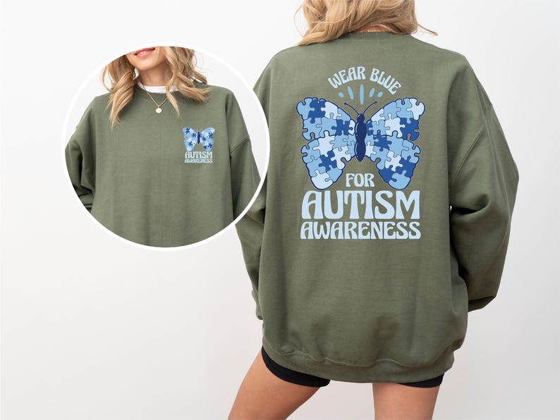Pu&ograve; includere: Felpa verde con una farfalla blu fatta di pezzi di puzzle sul retro. La farfalla ha il testo "Wear Blue for Autism Awareness".