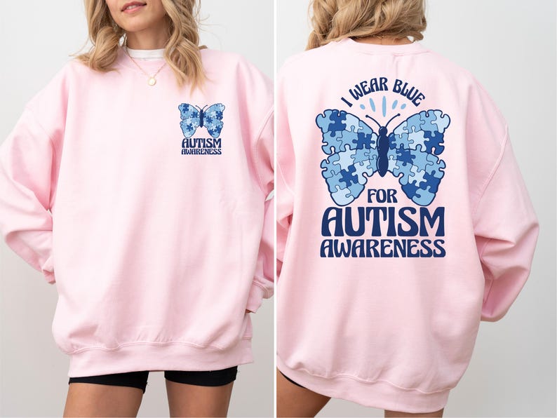 Pu&ograve; includere: Felpa rosa con una farfalla blu fatta di pezzi di puzzle sul retro. La farfalla ha il testo "Indossare il blu per la consapevolezza dell'autismo". La parte anteriore della felpa ha una farfalla blu pi&ugrave; piccola con il testo "Consapevolezza dell'autismo".