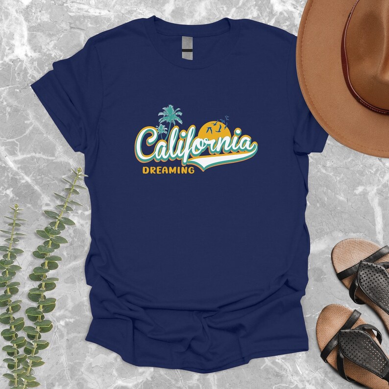 May include: A navy blue t-shirt with a retro-style graphic of palm trees, a sunset, and the text "California Dreaming".