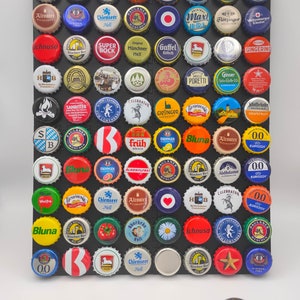 Könnte beinhalten: Eine Sammlung bunter Flaschenverschlüsse, die in einem Raster auf einem schwarzen Hintergrund angeordnet sind. Die Flaschenverschlüsse zeigen verschiedene Logos und Designs, darunter Biermarken, Brauereien und andere Getränke.