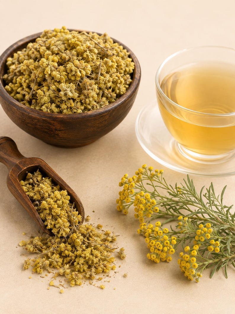 Peut inclure: Un bol en bois fonc&eacute; rempli de fleurs jaunes s&eacute;ch&eacute;es, une pelle en bois contenant d'autres fleurs s&eacute;ch&eacute;es, une tasse en verre transparent de th&eacute; jaune clair sur une soucoupe et un brin de fleurs jaunes fra&icirc;ches avec des tiges vertes.