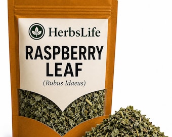 Op de afbeelding: Een bruine stazak met gedroogd frambozenblad, gelabeld HerbsLife RASPBERRY LEAF (Rubus Idaeus). De zak heeft een doorzichtig venster dat de groene, vermalen bladeren toont, met een hoopje van dezelfde gedroogde bladeren ernaast.