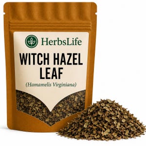 May include: A brown stand-up pouch containing dried witch hazel leaf, labelled HerbsLife Witch Hazel Leaf (Hamamelis Virginiana). A pile of the dark green, shredded dried leaves sits in front of the pouch, which features a clear window.