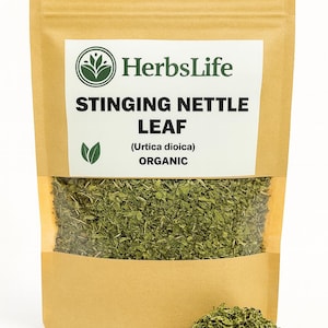 Könnte beinhalten: Ein brauner Papiersack mit einem transparenten Fenster, gefüllt mit getrockneten Brennnesselblättern. Der Beutel trägt das "HerbsLife"-Logo und den Text "Stinging Nettle Leaf (Urtica dioica) ORGANIC". Ein kleiner Haufen der getrockneten Blätter liegt davor.