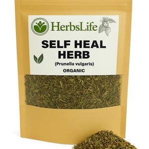 May include: A tan pouch of dried herbs labeled "HerbsLife SELF HEAL HERB (Prunella vulgaris) ORGANIC." The pouch is partially transparent, revealing the dried green herb inside. A small pile of the herb sits in front of the pouch.