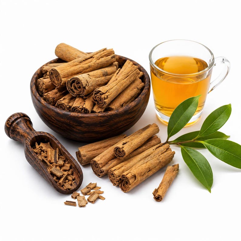 May include: A dark wooden bowl filled with brown cinnamon sticks, a matching wooden scoop containing cinnamon bark pieces, a clear glass mug filled with amber-coloured tea, and a small green leafy branch arranged on a white background.