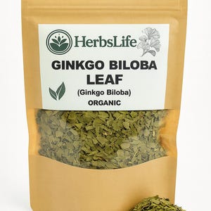 Puede incluir: Un paquete de hojas de Ginkgo Biloba orgánicas de HerbsLife. El paquete es de color marrón claro con una ventana transparente que muestra las hojas verdes. El texto en el paquete dice "Ginkgo Biloba Leaf" y "Organic". Un pequeño montón de hojas está frente al paquete.