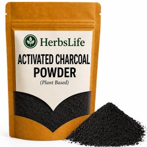 Pode incluir: Uma bolsa vertical castanha contendo pó de carvão ativado com um rótulo branco apresentando o logótipo HerbsLife e o texto ACTIVATED CHARCOAL POWDER (Plant Based). Um pequeno monte de pó preto fino encontra-se à frente da bolsa.