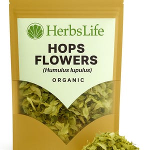 Puede incluir: Un paquete de flores de lúpulo orgánico, etiquetado como "HerbsLife". El paquete dorado tiene una ventana transparente que muestra el lúpulo verde. El texto dice "HOPS FLOWERS (Humulus lupulus) ORGANIC". Un pequeño montón de lúpulo está al lado.
