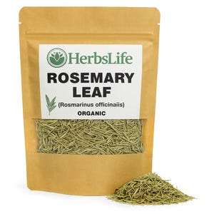 Op de afbeelding: Een bruine papieren zak met biologisch rozemarijnblad met een doorzichtig venster en een kleine hoop rozemarijnbladeren. De zak heeft het opschrift "HerbsLife ROSEMARY LEAF (Rosmarinus officinalis) ORGANIC".