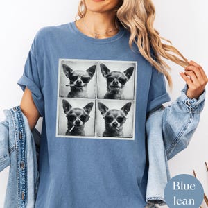 Pu&ograve; includere: T-shirt blu jeans con un'immagine a quattro pannelli di un chihuahua con occhiali da sole e una sigaretta. Il cane &egrave; in una foto in bianco e nero. La maglietta ha un girocollo e maniche corte.