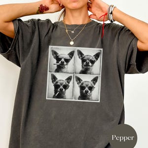 Pu&ograve; includere: T-shirt grigio scuro con una grafica quadrata di quattro immagini in bianco e nero di un Chihuahua con occhiali da sole, alcuni con sigarette. La maglietta ha una vestibilit&agrave; ampia.