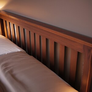 May include: A wooden headboard with vertical slats, featuring a rich brown finish. The headboard is made of solid wood and has a simple, elegant design.