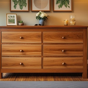 Puede incluir: Una cómoda de seis cajones hecha de madera marrón claro con un acabado de veta de madera natural. La cómoda tiene pomos redondos simples en cada cajón. La cómoda está sobre un suelo de madera marrón claro.