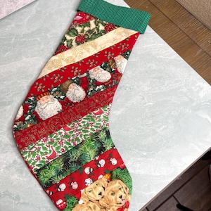 May include: A Christmas stocking featuring a patchwork design of diagonal fabric strips. The patterns include Santa Claus faces, holly leaves, pine branches, snowmen, and golden puppies. It has a green polka dot cuff and a matching hanging loop.