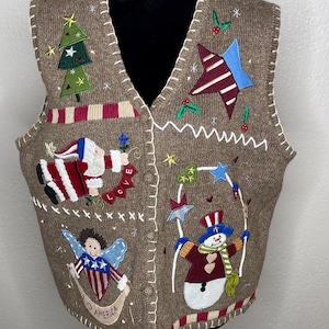 May include: Brown knitted vest with Christmas and patriotic themed appliqués. Features a Christmas tree, star, Santa Claus, angel, and snowman designs. The vest has a V-neck and button closure, with red and white striped trim.